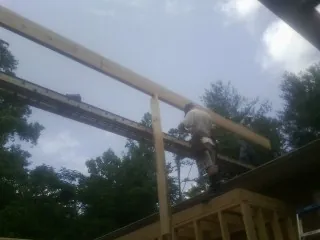 Carpenter setting a ridge beam over a new addition frame — Ice Dam Removal by Roofing Brothers in Pratts