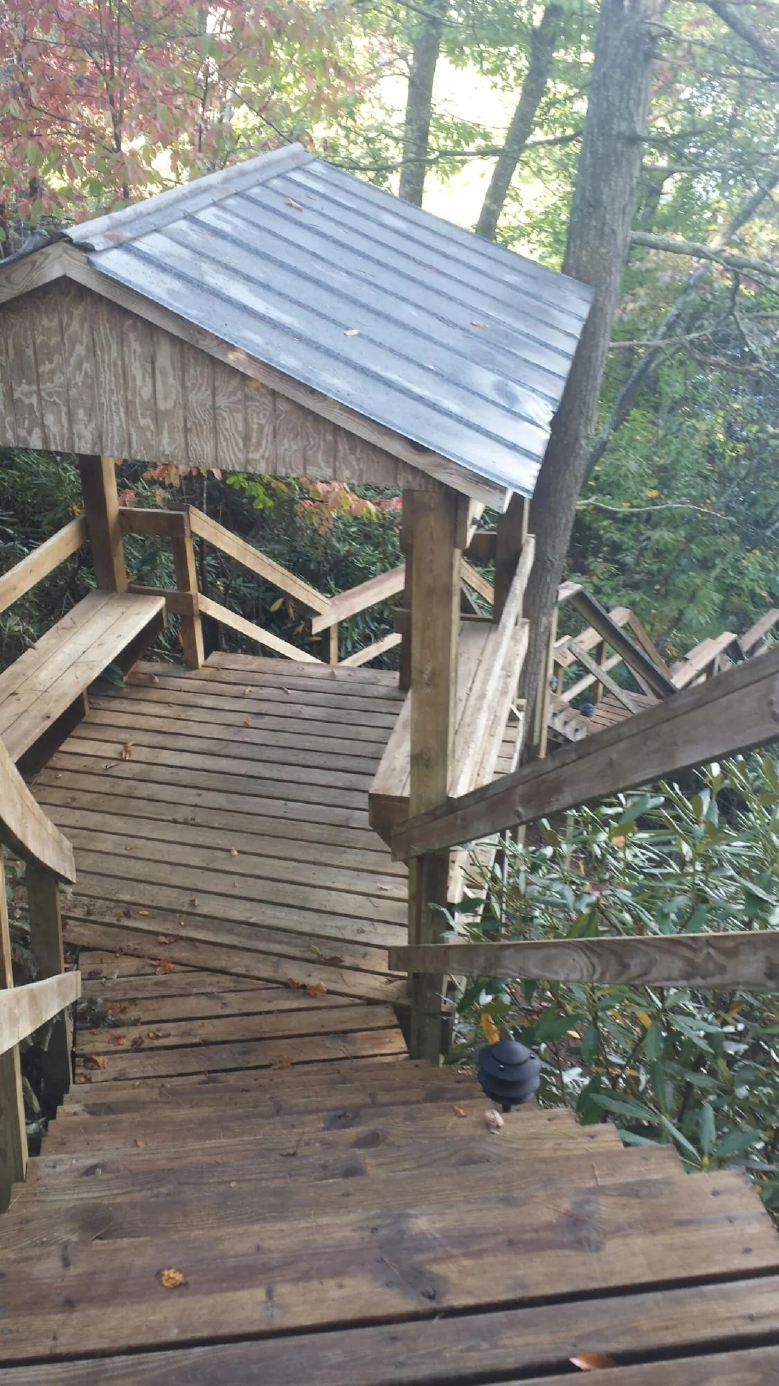 Metal roofed shelter over wooden steps on a wooded walkway — Skylight Repair & Installation work by our crew in Pratts