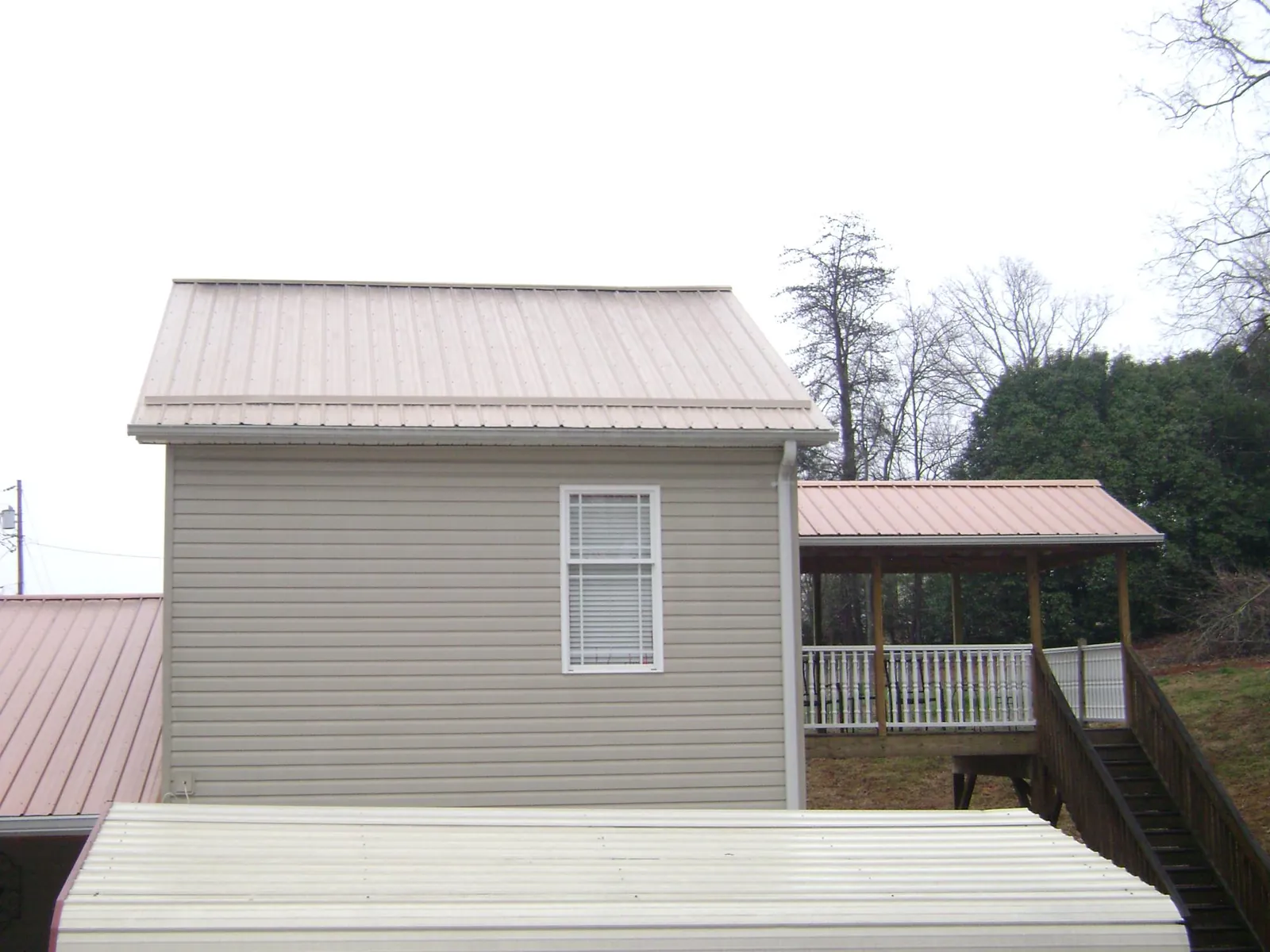 Tan metal roofs on a two story addition and attached porch, from a Roof Replacement job in Pratts