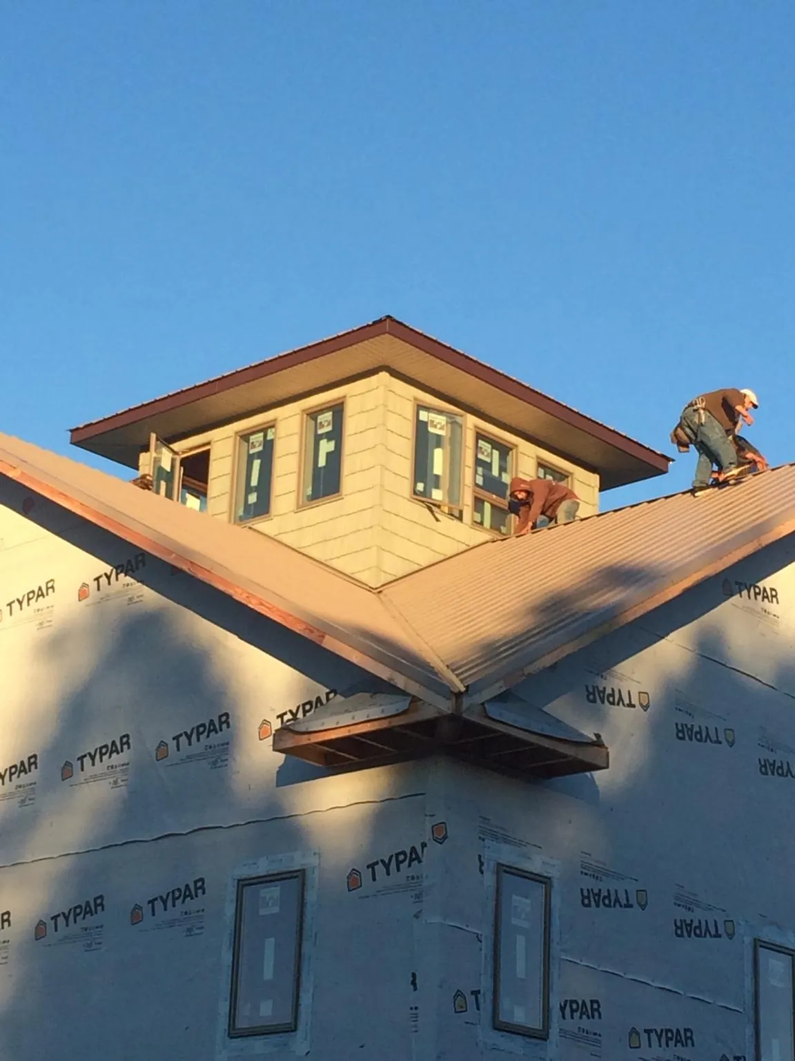 Roofers working around a rooftop cupola on a new metal roof at sunset — Roof Waterproofing in Pratts by Roofing Brothers